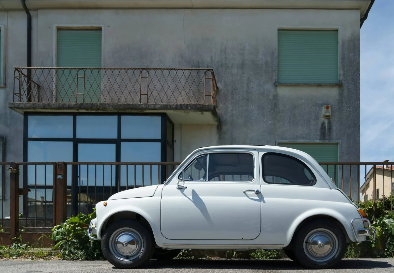 A vintage Fiat 500 parked by a house with green shutters in the province of Vicenza