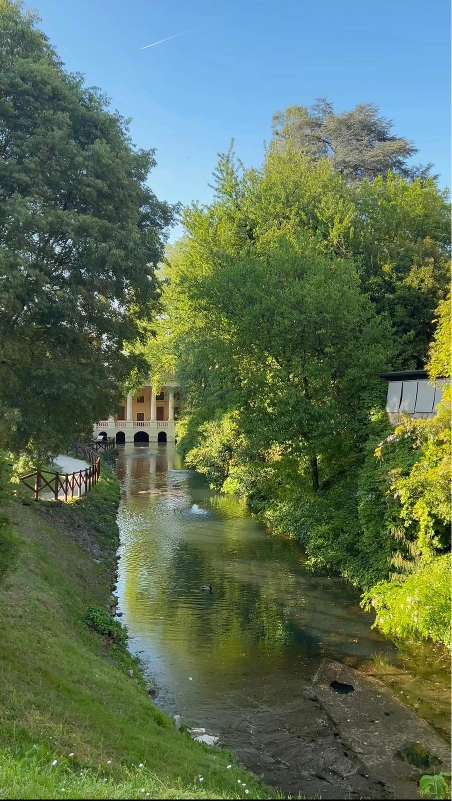 A tree-lined canal in Vicenza leading to an arcaded pavilion
